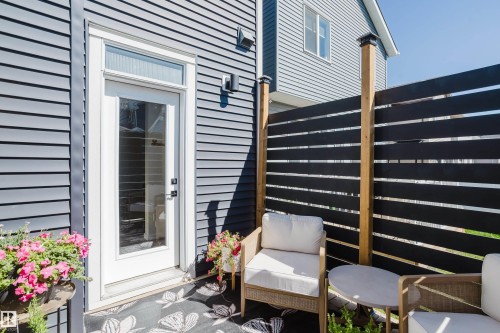 Private outdoor deck featuring horizontal slat fencing, a glass-paned exterior door, and dark horizontal siding - 7017 52 Avenue, Beaumont, AB 