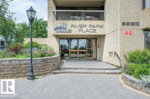 Building entrance with glass doors, stone facade, and a prominent building name - #904 8220 Jasper Av Nw, Edmonton, AB 