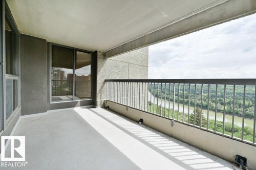 Expansive balcony featuring concrete flooring, a metal railing, and a scenic river backdrop - #904 8220 Jasper Av Nw, Edmonton, AB 