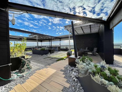 Rooftop terrace with solar panel array, wood planking, gravel, and artificial turf sections - #904 8220 Jasper Av Nw, Edmonton, AB 