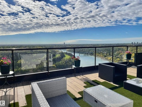 Expansive outdoor terrace featuring a glass railing, wood-finish flooring, and integrated artificial turf accents - #904 8220 Jasper Av Nw, Edmonton, AB 