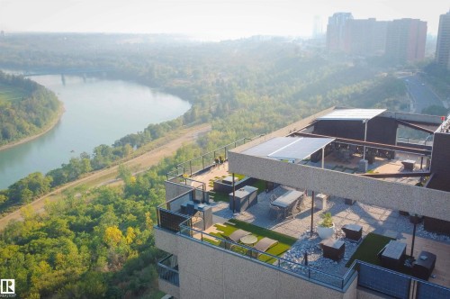 Expansive rooftop patio featuring a river backdrop, multiple seating areas, a built-in outdoor kitchen, and overhead awnings - #904 8220 Jasper Av Nw, Edmonton, AB 
