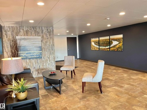 Recessed lighting, tile flooring, accent wall with stacked stone finish, dark painted wall, and a dark wood-finish door - #904 8220 Jasper Av Nw, Edmonton, AB 