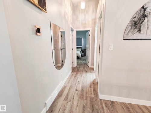 Hallway featuring wood-finish flooring, light-toned wall paint, and a ceiling-mounted pendant light fixture - 215 Peter Close Nw, Edmonton, AB 