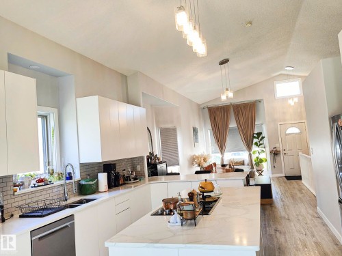 Modern kitchen featuring white cabinetry, light-colored countertops, a tile backsplash, and stainless steel appliances - 215 Peter Close Nw, Edmonton, AB 