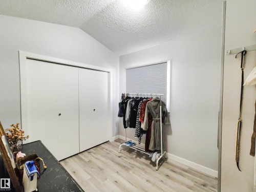 Sliding closet doors, window with blinds, vaulted ceiling, and wood-finish flooring - 215 Peter Close Nw, Edmonton, AB 