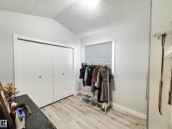 Sliding closet doors, window with blinds, vaulted ceiling, and wood-finish flooring - 