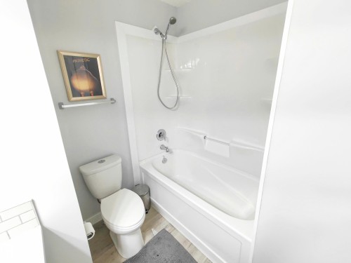 White bathtub with integrated shower, chrome fixtures, and a white toilet - 215 Peter Close Nw, Edmonton, AB 