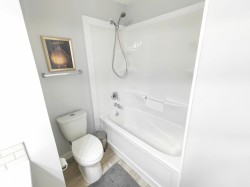 White bathtub with integrated shower, chrome fixtures, and a white toilet - 