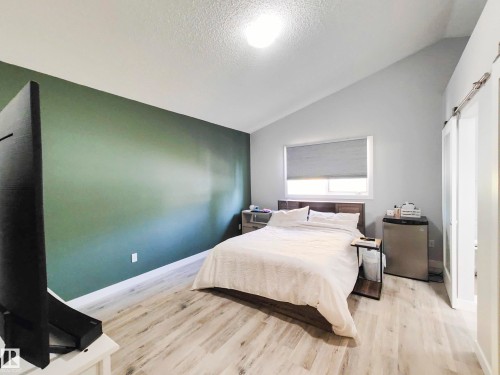 Vaulted ceiling, wood-finish flooring, accent wall, and window with roller shade - 215 Peter Close Nw, Edmonton, AB 