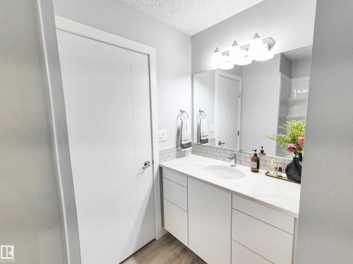 White vanity with integrated rectangular sink, stone-finish countertop, and white subway tile backsplash - 215 Peter Close Nw, Edmonton, AB 