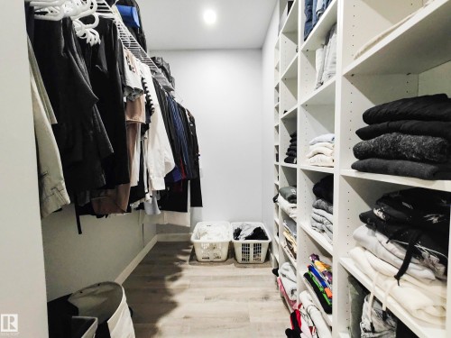 Walk-in closet featuring built-in shelving, hanging storage, wood-finish flooring, and recessed lighting - 215 Peter Close Nw, Edmonton, AB 