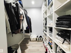 Walk-in closet featuring built-in shelving, hanging storage, wood-finish flooring, and recessed lighting - 