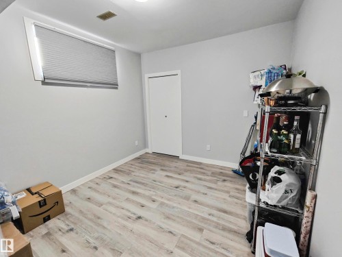Light wood-finish flooring, neutral gray walls, a window with blinds, and a white door with a black knob - 215 Peter Close Nw, Edmonton, AB 