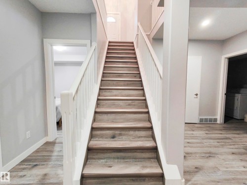 Wood-finish flooring throughout, white stair railing, and neutral wall tones - 215 Peter Close Nw, Edmonton, AB 