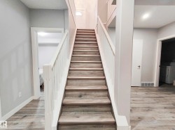 Wood-finish flooring throughout, white stair railing, and neutral wall tones - 
