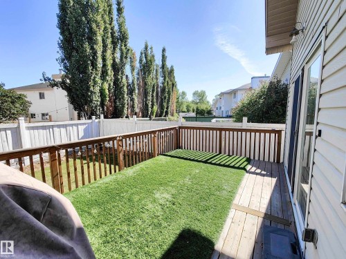 Private backyard featuring a wooden deck, artificial turf, and a white privacy fence - 215 Peter Close Nw, Edmonton, AB 