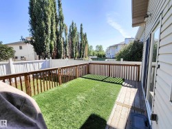 Private backyard featuring a wooden deck, artificial turf, and a white privacy fence - 