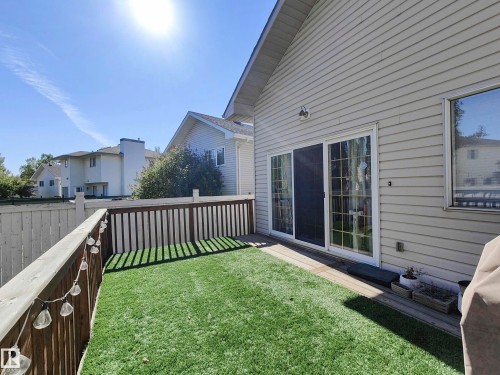 Private outdoor deck space featuring artificial turf, wood fencing, and sliding glass doors - 215 Peter Close Nw, Edmonton, AB 