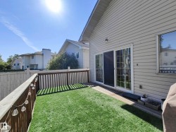 Private outdoor deck space featuring artificial turf, wood fencing, and sliding glass doors - 