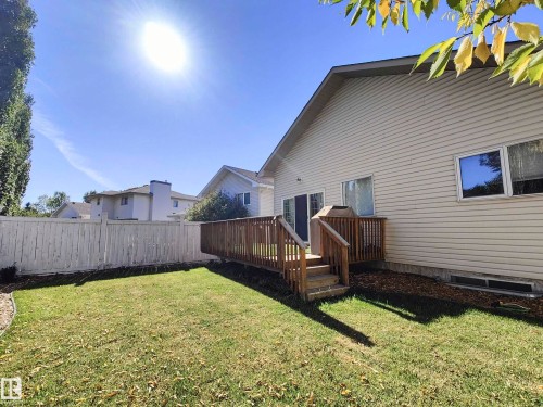 Expansive lawn area, wood-plank deck with railings, wood privacy fencing, and neutral-toned siding - 215 Peter Close Nw, Edmonton, AB 