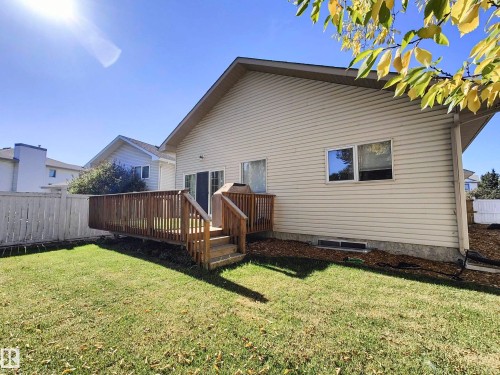 Expansive backyard featuring a wood deck with steps, a sliding glass door, and a white picket fence - 215 Peter Close Nw, Edmonton, AB 