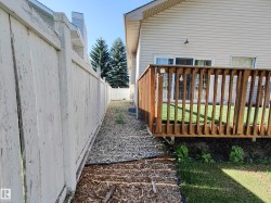 Exterior wood deck with railings, sliding glass door access, and a gravel pathway - 