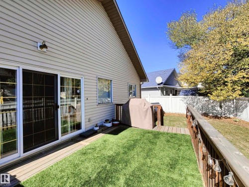 Patio featuring a sliding glass door, composite decking, and a fenced yard with natural grass - 215 Peter Close Nw, Edmonton, AB 