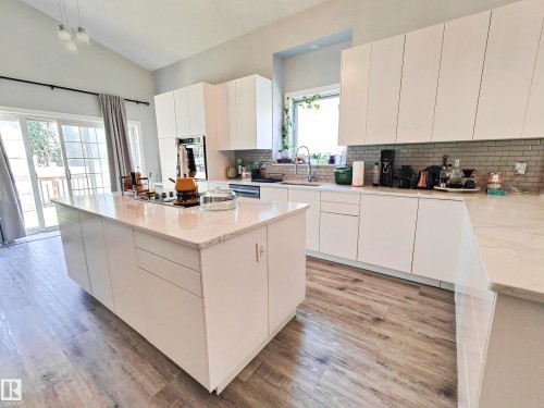 Vaulted ceilings, wood-finish flooring, white flat-panel cabinetry, light-toned countertops, and a subway tile backsplash - 215 Peter Close Nw, Edmonton, AB 