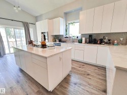 Vaulted ceilings, wood-finish flooring, white flat-panel cabinetry, light-toned countertops, and a subway tile backsplash - 