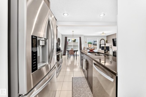 Stainless steel refrigerator, tile flooring, built-in kitchen island, stainless steel dishwasher, and recessed lighting - 16832 53 Street Nw, Edmonton, AB 