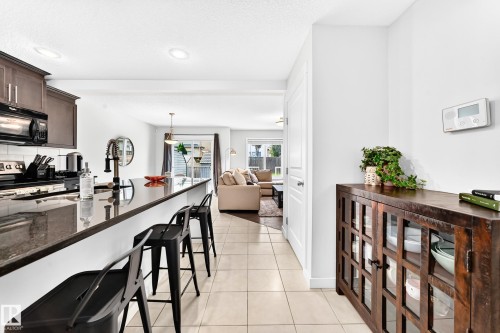 Kitchen featuring dark wood-finish cabinetry, a black range, and a tile backsplash - 16832 53 Street Nw, Edmonton, AB 