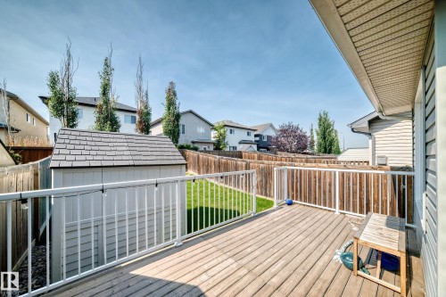 Spacious wood-finish deck with white railings, a grass lawn, privacy fencing, and a built-in storage shed - 16832 53 Street Nw, Edmonton, AB 