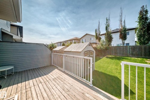 Wood-finish deck with white railings, a private side wall, a shed with a shingle roof, and a manicured lawn - 16832 53 Street Nw, Edmonton, AB 