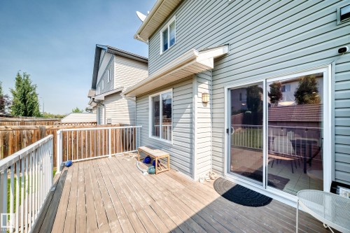 Wooden deck with white railing, vinyl siding exterior, and sliding glass door - 16832 53 Street Nw, Edmonton, AB 
