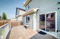 Wooden deck with white railing, vinyl siding exterior, and sliding glass door - 