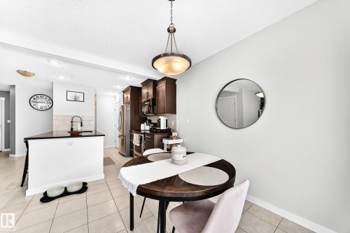 Kitchen featuring dark wood-finish cabinetry, stainless steel appliances, and a tiled backsplash - 16832 53 Street Nw, Edmonton, AB 