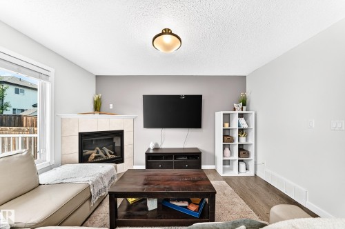 Corner fireplace with tile surround, wood-finish flooring, and recessed ceiling light fixture - 16832 53 Street Nw, Edmonton, AB 