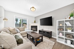 Living space featuring wood-finish flooring, a white mantel fireplace, and a large window with exterior visibility - 