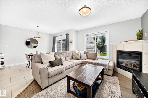 Living area featuring a tiled fireplace with mantel, window, wood-finish flooring, and recessed lighting - 16832 53 Street Nw, Edmonton, AB 