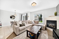 Living area featuring a tiled fireplace with mantel, window, wood-finish flooring, and recessed lighting - 