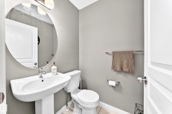 Pedestal sink with chrome faucet, circular wall mirror, wall-mounted light fixture, and tile flooring - 