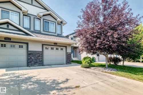 Exterior featuring horizontal siding, stone veneer accents, multiple windows, and two garage doors - 16832 53 Street Nw, Edmonton, AB 
