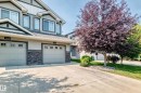 Exterior featuring horizontal siding, stone veneer accents, multiple windows, and two garage doors - 16832 53 Street Nw, Edmonton, AB 