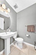 Pedestal sink with chrome faucet, round wall-mounted mirror, ceramic tile flooring, and integrated ceiling ventilation - 