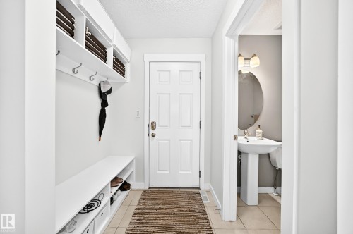 Built-in storage bench with open shelving, wall-mounted coat hooks, and a paneled entry door - 16832 53 Street Nw, Edmonton, AB 