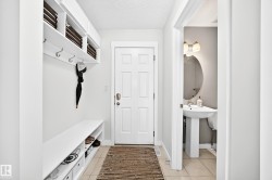 Built-in storage bench with open shelving, wall-mounted coat hooks, and a paneled entry door - 
