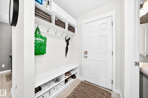 White built-in storage bench with integrated shelving, overhead cabinets, and wall-mounted hooks - 16832 53 Street Nw, Edmonton, AB 