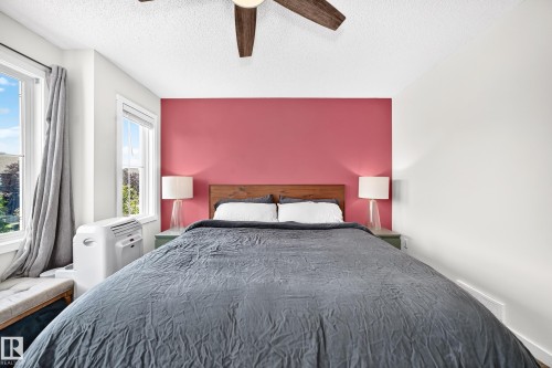Two large windows with white trim, a wood-finish ceiling fan, and a wood-finish headboard - 16832 53 Street Nw, Edmonton, AB 