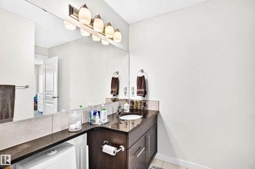 Integrated vanity with an undermount sink, dark countertop, and dark wood-finish cabinetry - 16832 53 Street Nw, Edmonton, AB 